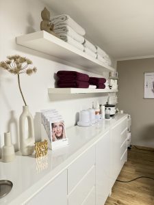 Arbeitskommode mit Hautpflegeprodukten und Dekoration im Behandlungsraum von Samtweich Cosmetic, Kosmetikstudio Landsberg am Lech